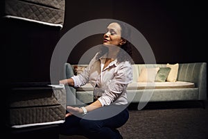 A sales manager, retailer, warehouse worker lays out samples of orthopedic mattresses on a stand. Furniture store, home design