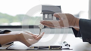 Sales manager or salesperson holds a demo house and has a home purchase contract with keys