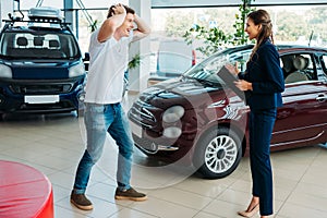 Sales manager showing to happy and surprised customer a car