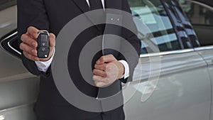 Sales manager shows key near the car