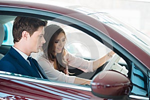 Sales Manager sitting in a new car with a beautiful customer