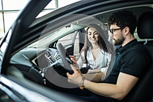 Sales manager woman describing car to customer in showroom