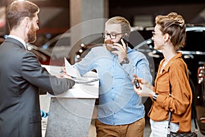 Sales manager with a young couple buying a new car