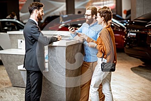 Sales manager with a young couple buying a new car