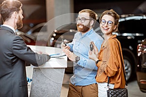 Sales manager with a young couple buying a new car