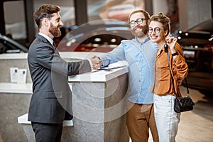Sales manager with a young couple buying a new car