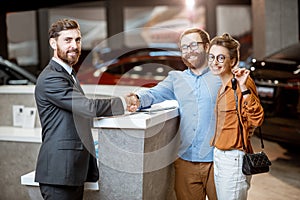 Sales manager with a young couple buying a new car