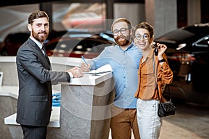 Sales manager with a young couple buying a new car