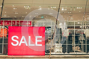 Sales promotion of women fashion clothes retail store in shopping mall, sale label sign sticker in front of shop door glasses