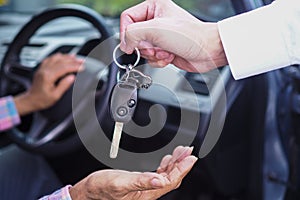 The sales representative is giving the car keys to the new owner in the car. Ideas for renting a car or buying a car