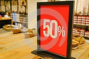 50 sales sign card in clothes store close-up across shelves with shoes and sneakers. Sales, discount, Black Friday, Cyber Monday,