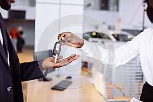 Sales situation in car dealership, young african couple gets the key for new car