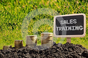 Sales training. Financial opportunity concept. Golden coins in soil Chalkboard on blurred urban background.