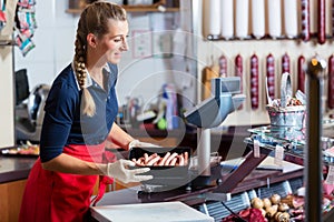 Sales woman in butcher shop putting different kinds of meat in display