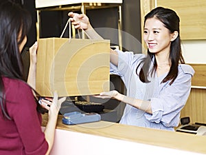 Salesclerk handing merchandise to customer