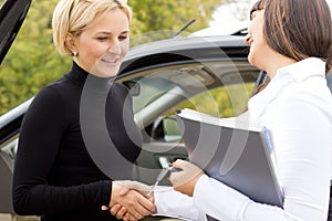 Saleslady congratulating a new car owner