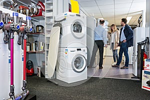 Salesman Assisting Couple In Buying Refrigerator