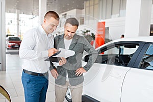 Salesman and buyer make out the purchase of car