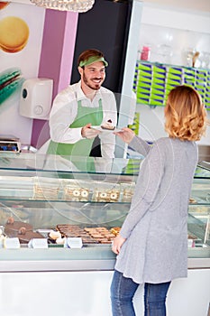 Salesman in candy shop gives cup cake to customer