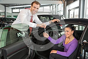 Salesman in car dealership sells automobile to customer