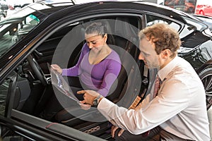 Salesman in car dealership sells automobile to customer