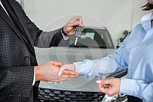 salesman car key handover from car sales to the owner at showroom