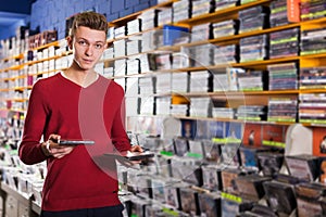 salesman of CD shop offering discs to somebody