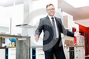 Salesman in domestic kitchen furniture showroom