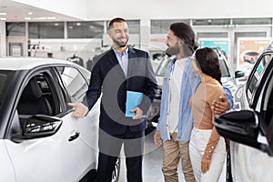 Salesman explaining car features to indian couple