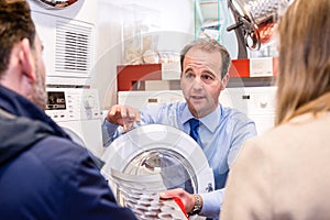 Salesman Explaining Product To Couple In Hypermarket