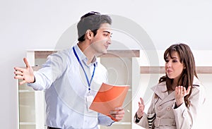 Salesman explaining to woman customer at furniture store