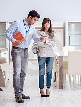 Salesman explaining to woman customer at furniture store