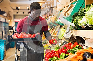 Salesman filling counter with red peppers