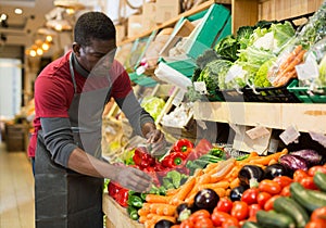 Salesman filling counter with vegetables and fruits