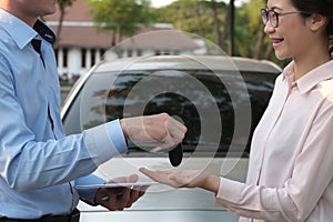 Salesman give car key to customer. woman buying car from dealer.