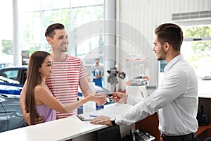 Salesman giving car key to happy couple