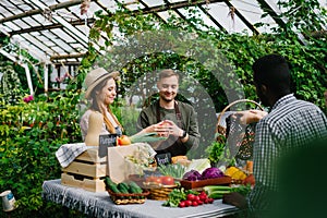 Salesman giving organic products to customers in greenhouse farm market