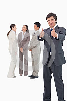 Salesman giving thumbs up with colleagues behind him