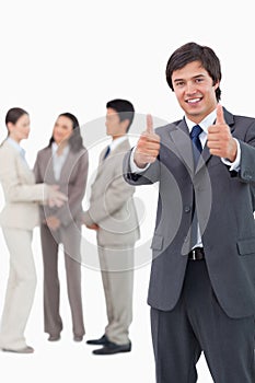 Salesman giving thumbs up with team behind him