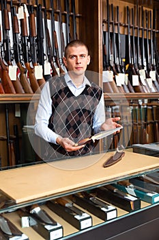 Salesman in gun shop demonstrates hunting knife for finishing off wounded animals