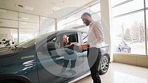 Salesman helping woman choose luxury car at vehicle dealership