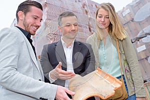 Salesman holding modern rooftile for couple to see