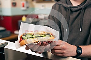 Salesman with hotdog in fast food snack bar