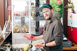 Salesman making hotdog in fast food snack bar