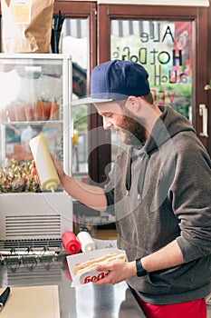 Salesman making hotdog in fast food snack bar