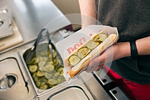 Salesman making hotdog in fast food snack bar