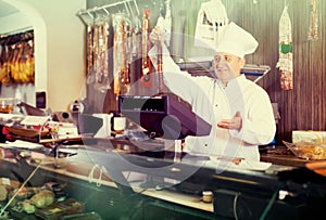 Salesman offering different sausages in market