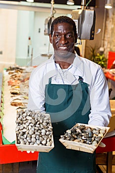 Salesman offering fresh clams in fish store