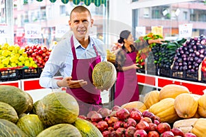 Salesman offering ripe melon in fruit and vegetable store