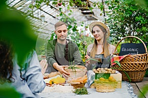 Salesman packing vegetables in paper bag during farm sale when wife taking notes